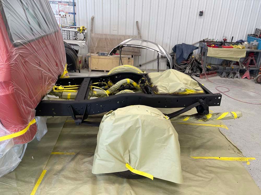 A red truck is being painted in a garage.