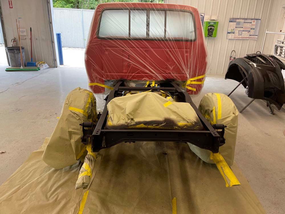 A red truck is being painted in a garage.