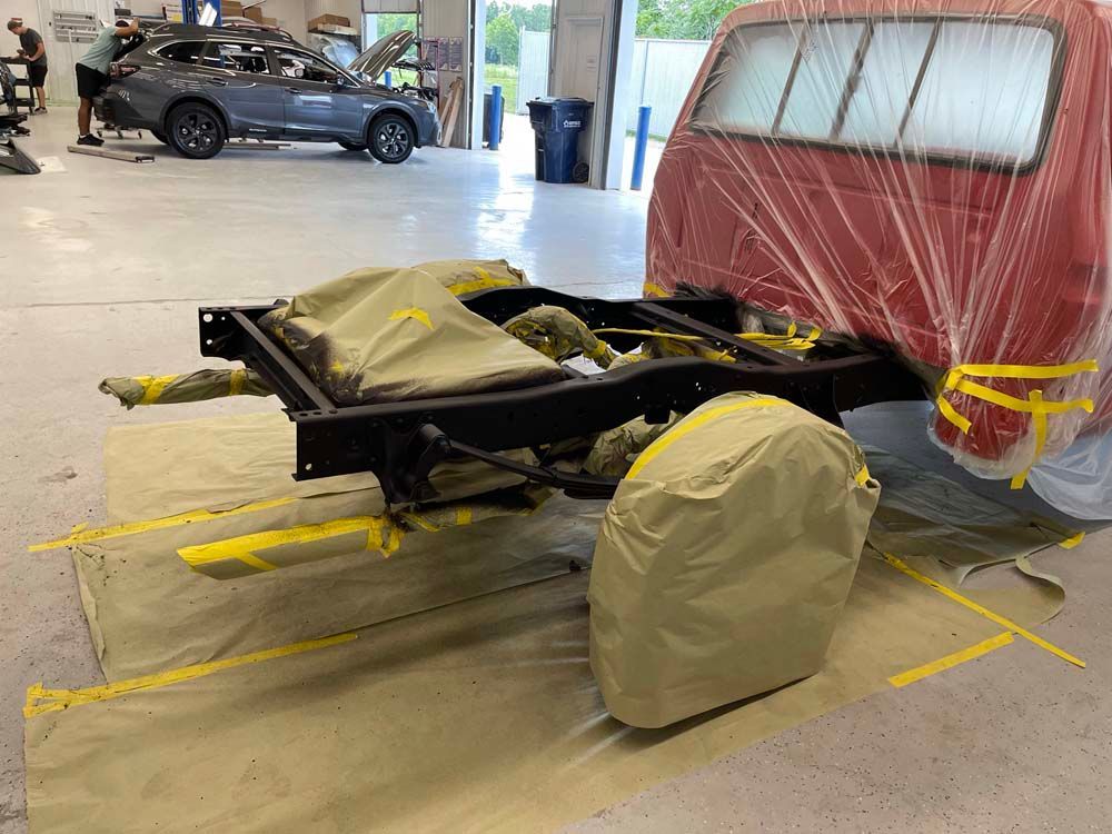 A red truck is being painted in a garage.