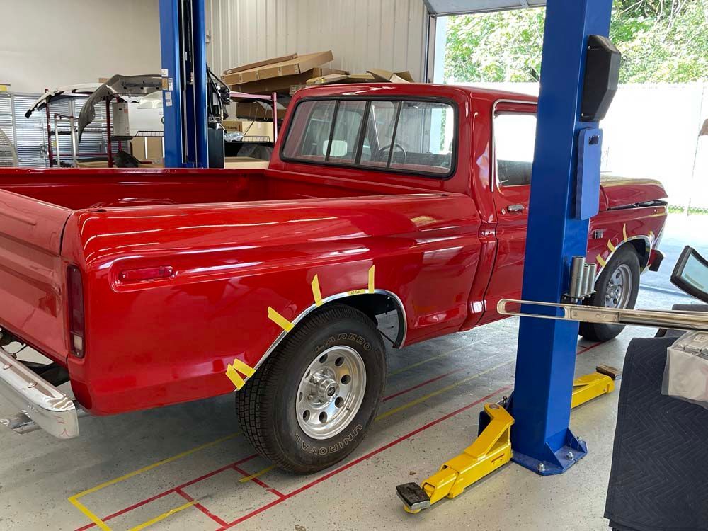 A red truck is on a lift in a garage.