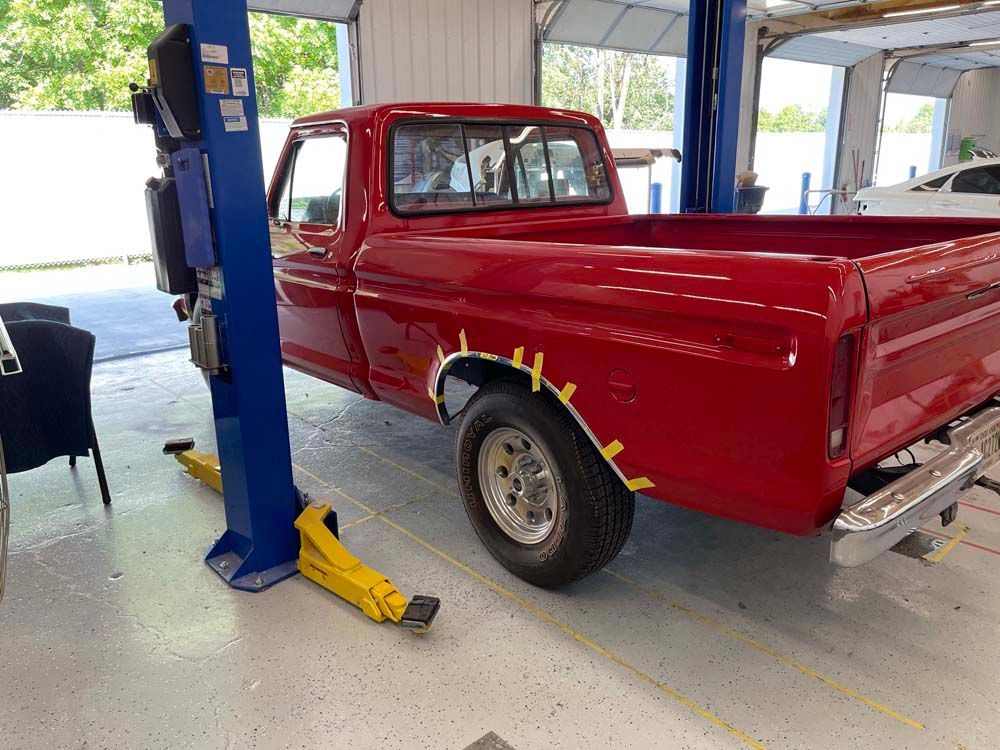 A red truck is parked on a lift in a garage.