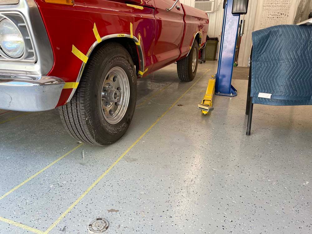 A red truck is parked in a garage with yellow tape on the fenders