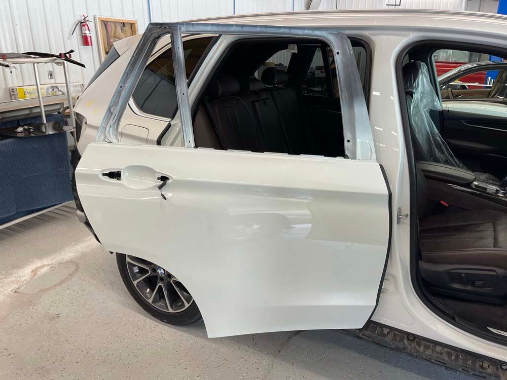A white car with the door open is sitting in a garage.
