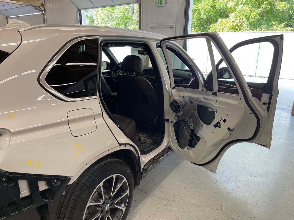 A white bmw x5 with its doors open in a garage.