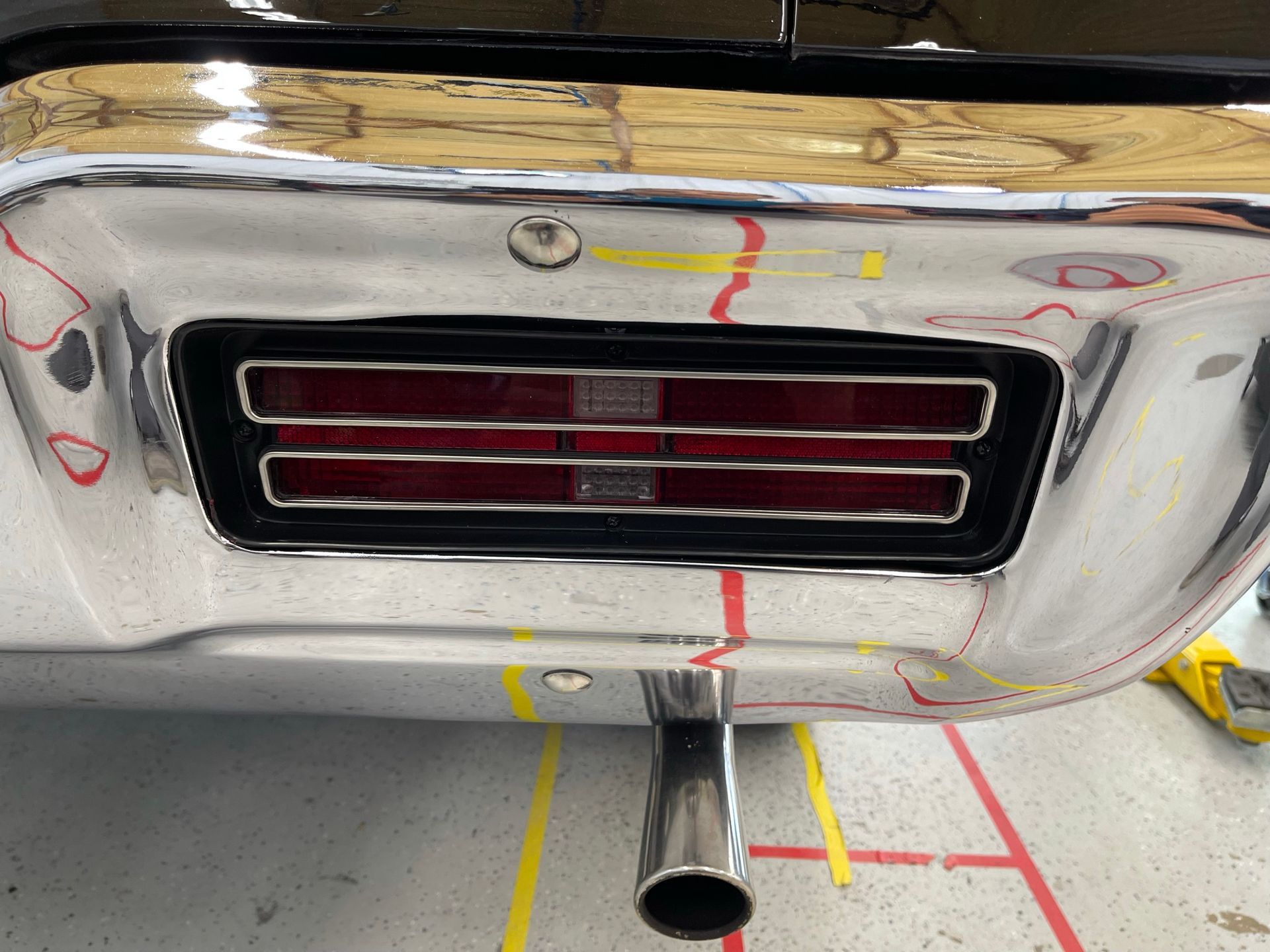 A close up of a car 's tail light and exhaust pipe