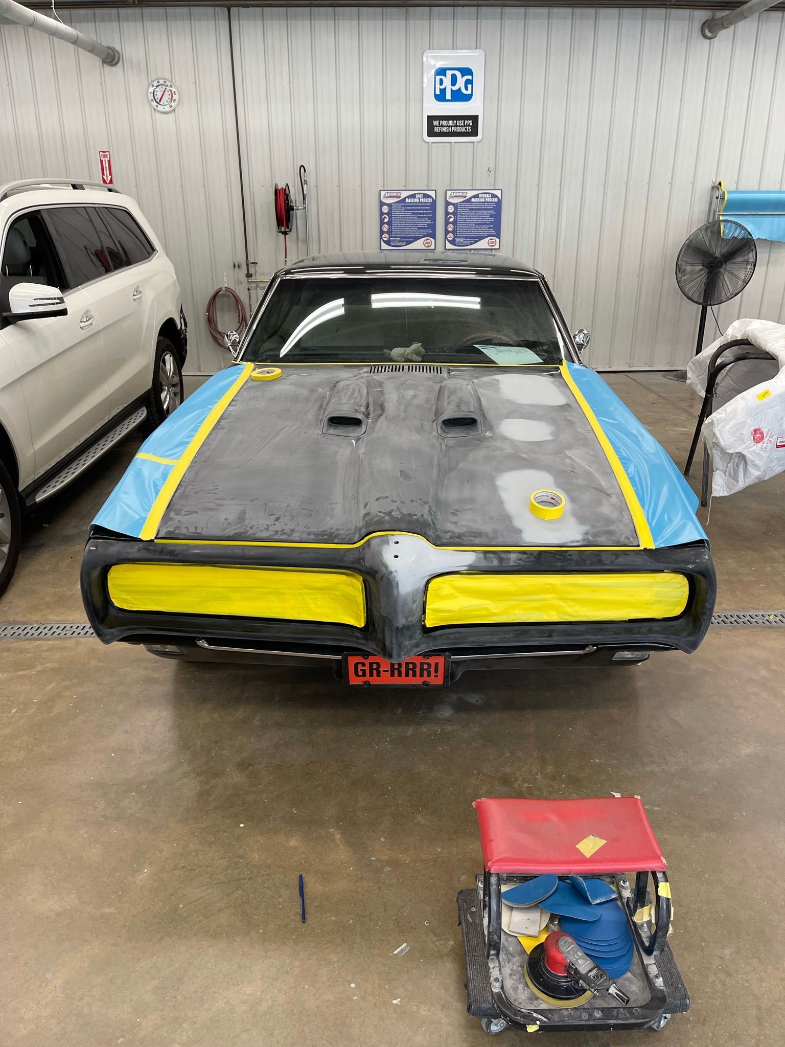 A blue and yellow car is sitting in a garage.