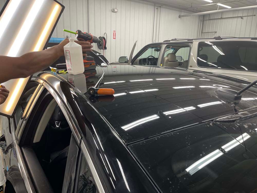 A person is spraying water on the roof of a car.