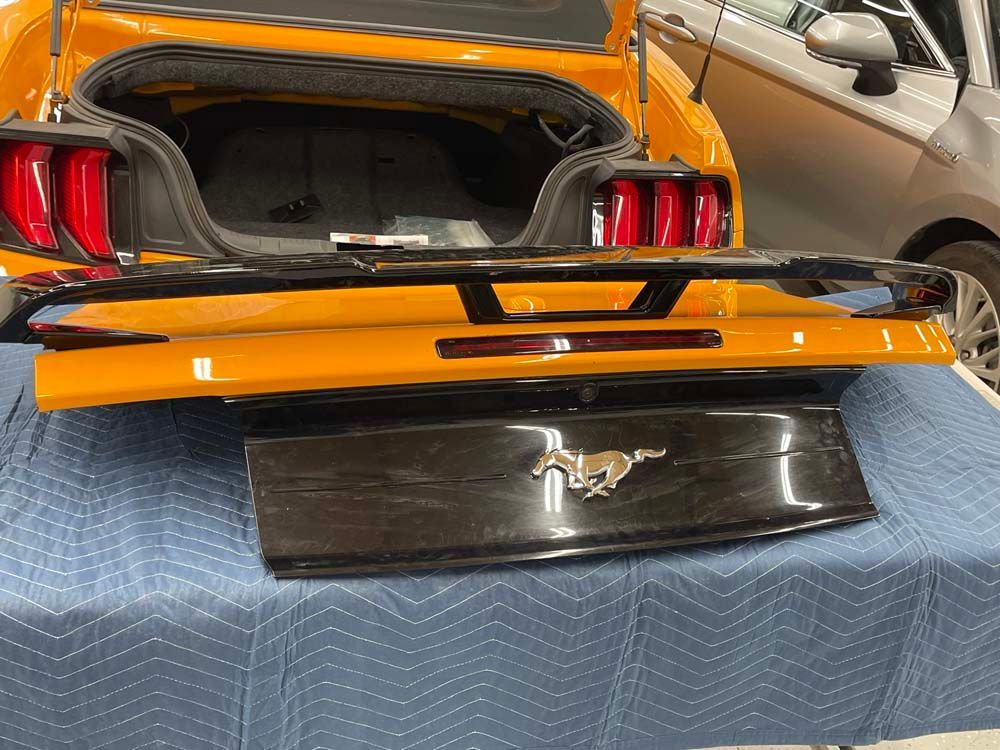 A yellow mustang with the trunk open is sitting on a table.