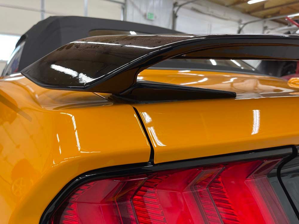 A close up of a yellow car with a spoiler on the back of it.