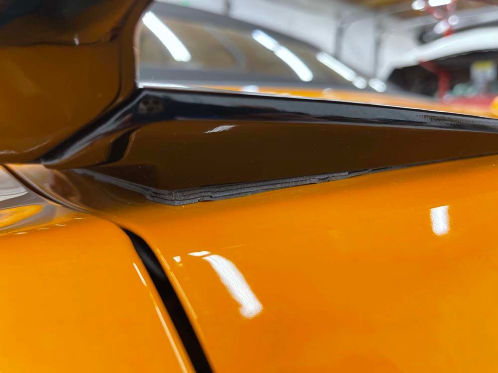A close up of a yellow car in a garage.