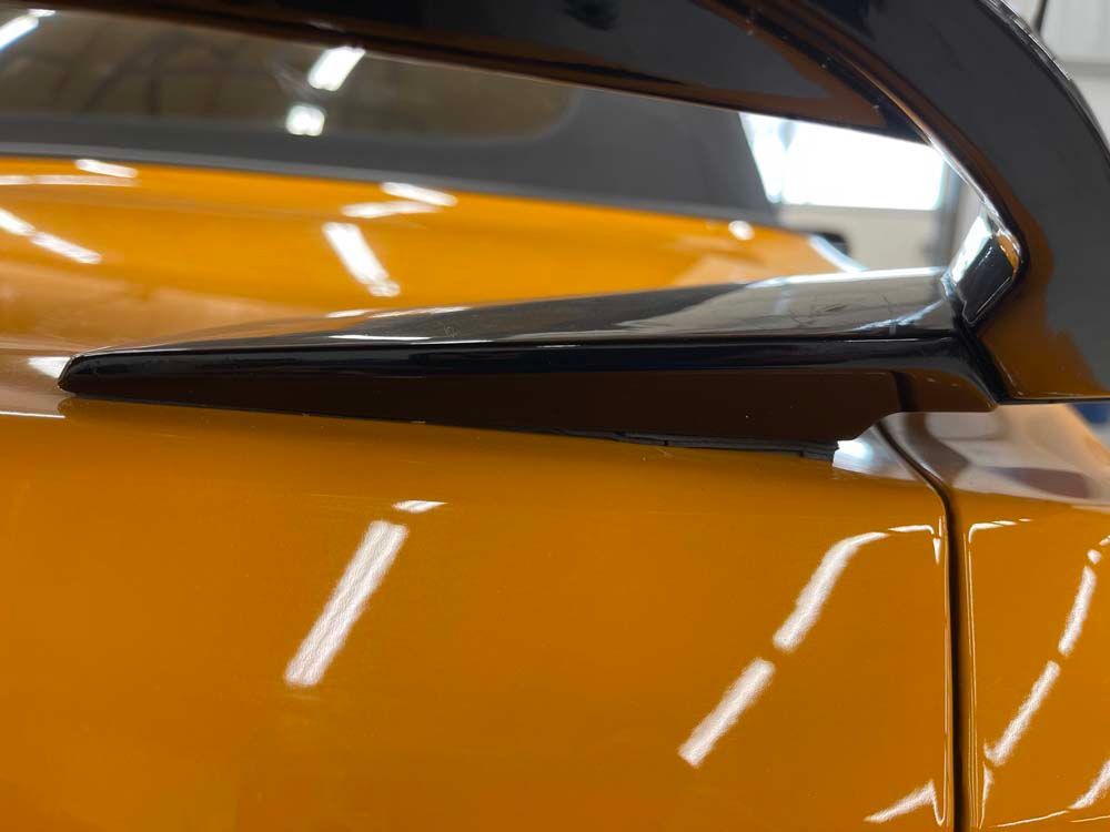 A close up of a yellow car with a black side mirror