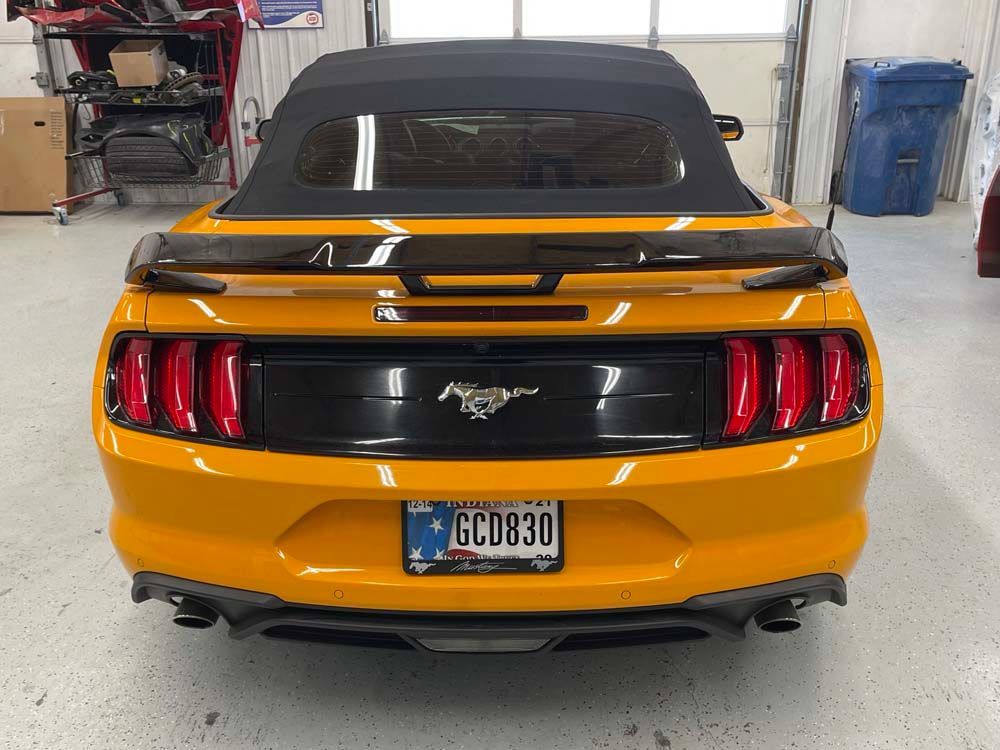 A yellow mustang convertible with a license plate that says gcd830