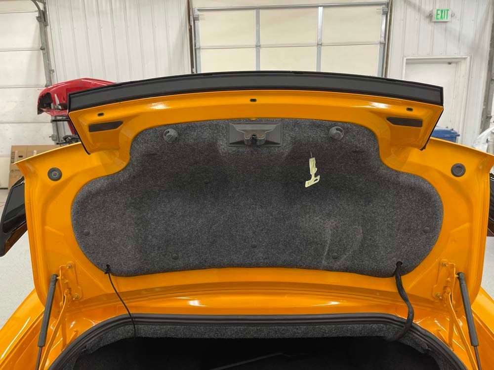 The back of a yellow car with the trunk open.