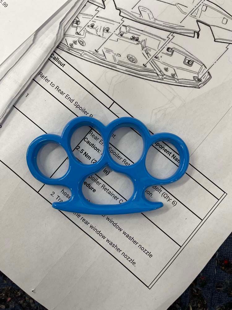 A blue knuckle duster is sitting on top of a piece of paper