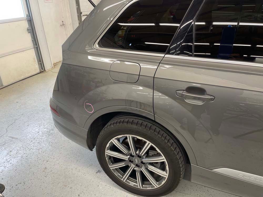 A gray audi q7 is parked in a garage.