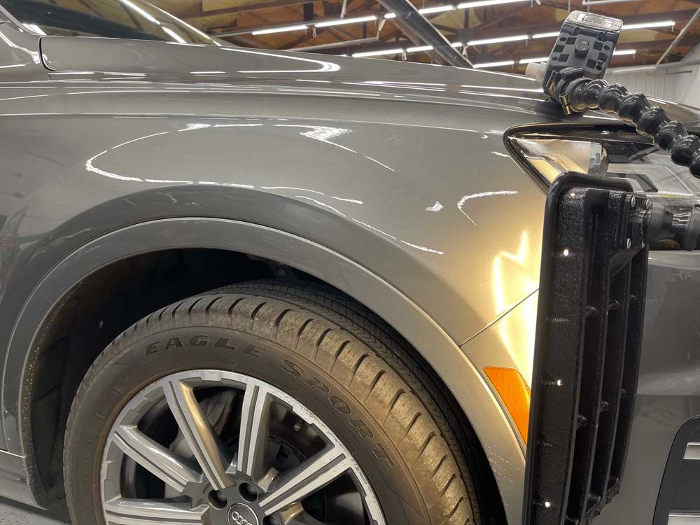 A close up of a car 's fender with a camera attached to it.