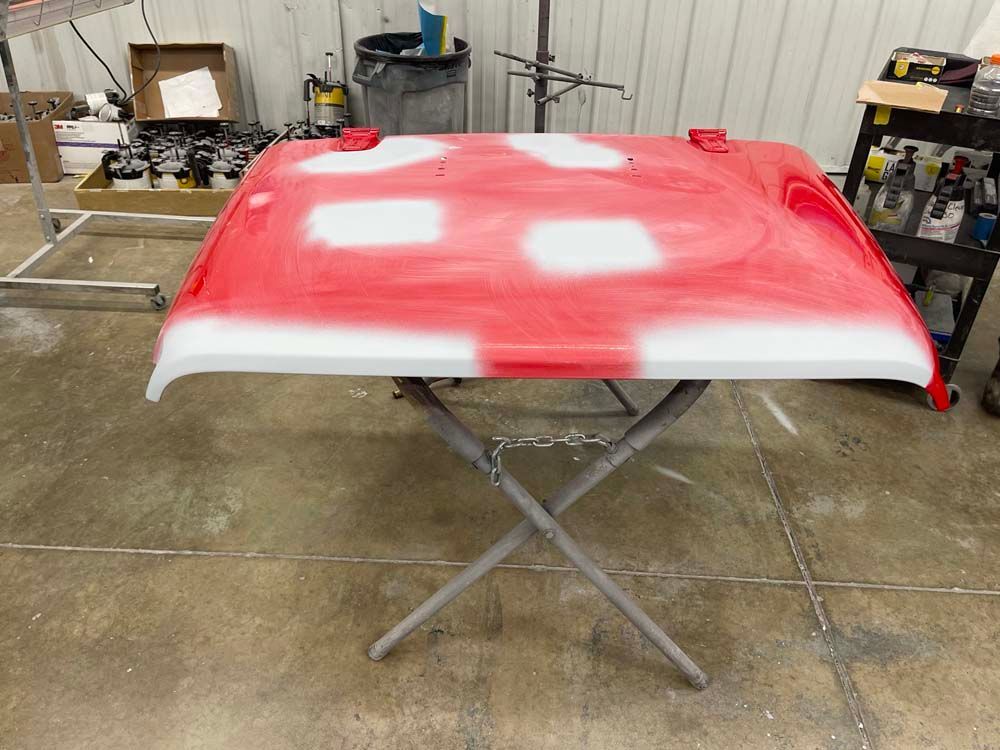 A red and white hood is sitting on a table in a garage.
