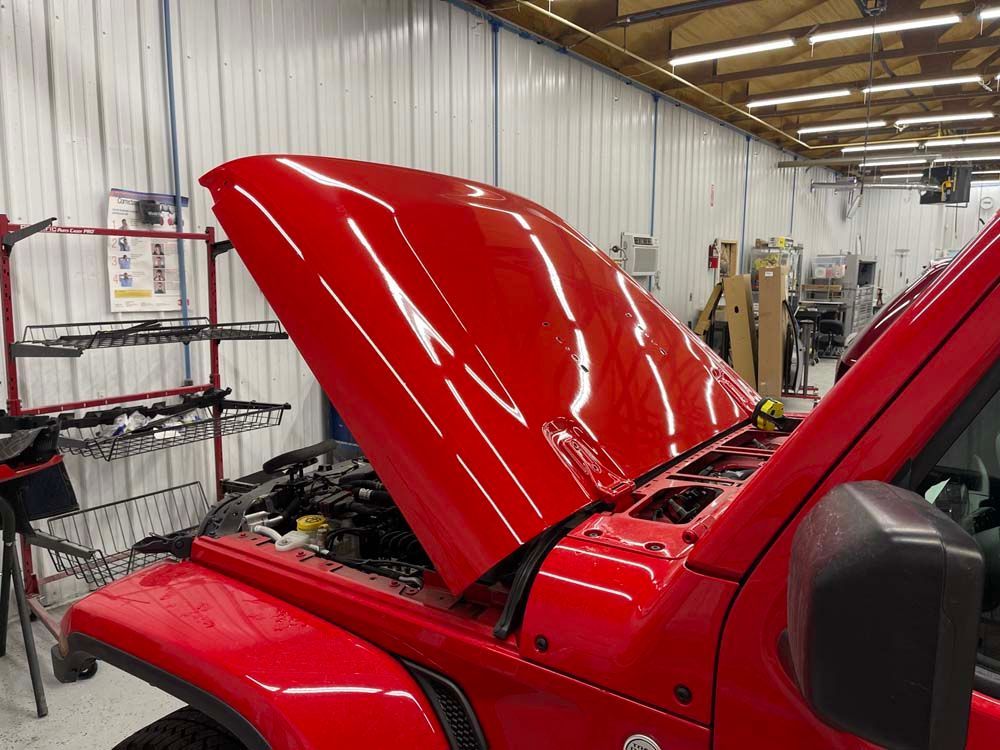 A red jeep with the hood open in a garage