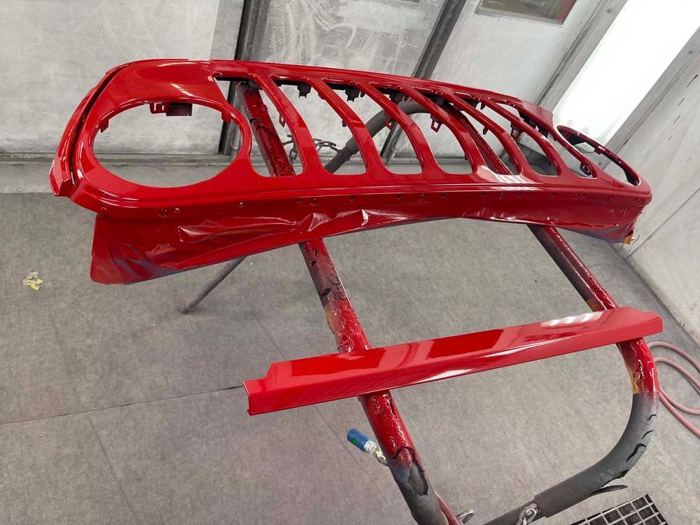 A red grille is sitting on a stand in a paint booth