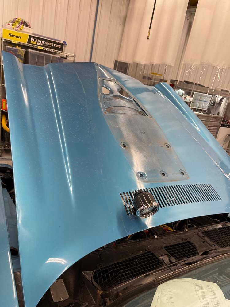 A close up of a blue car hood in a garage.