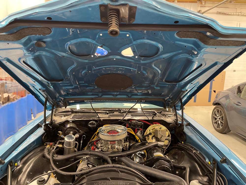 The hood of a blue car is open and the engine is visible.