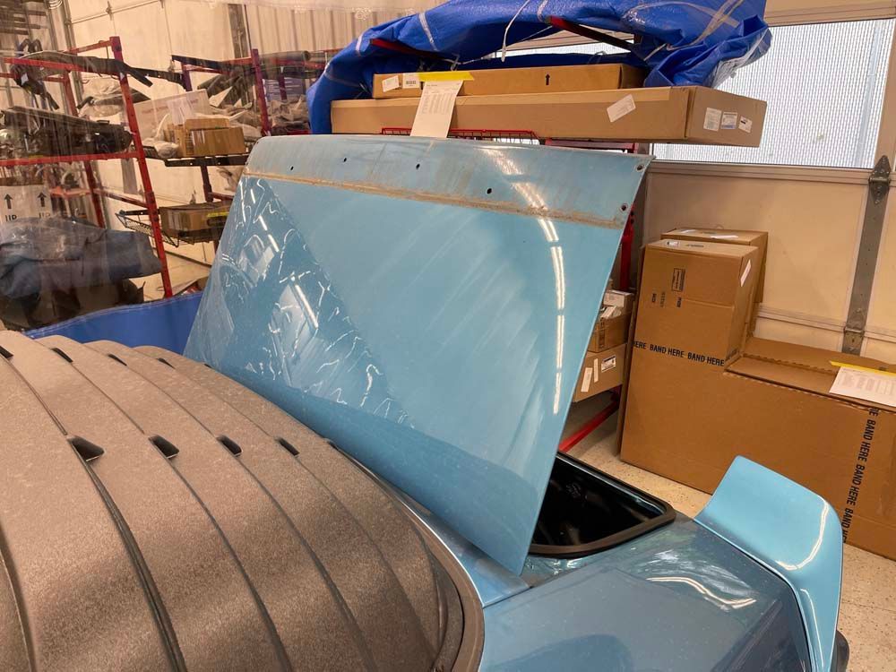 A blue car with the hood open in a garage.