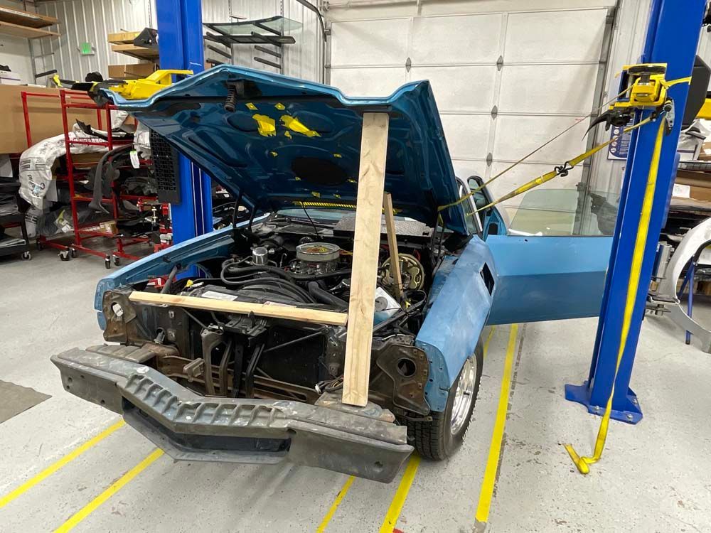 A blue car is sitting on a lift in a garage.