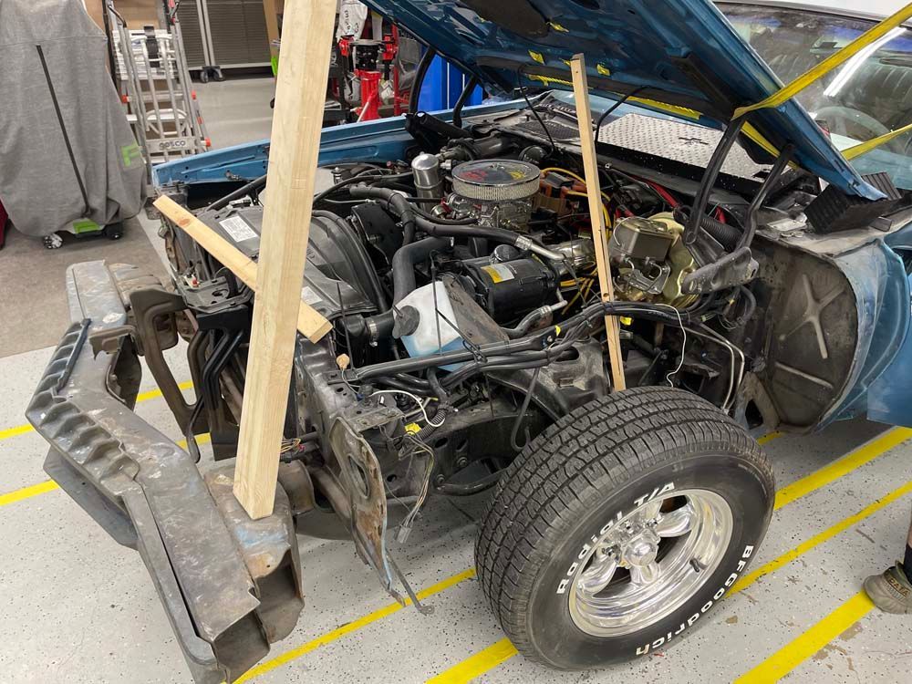 A blue car is being dismantled in a garage.