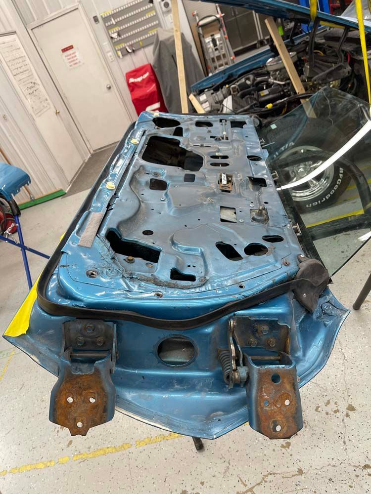 A blue car door is sitting on a table in a garage.