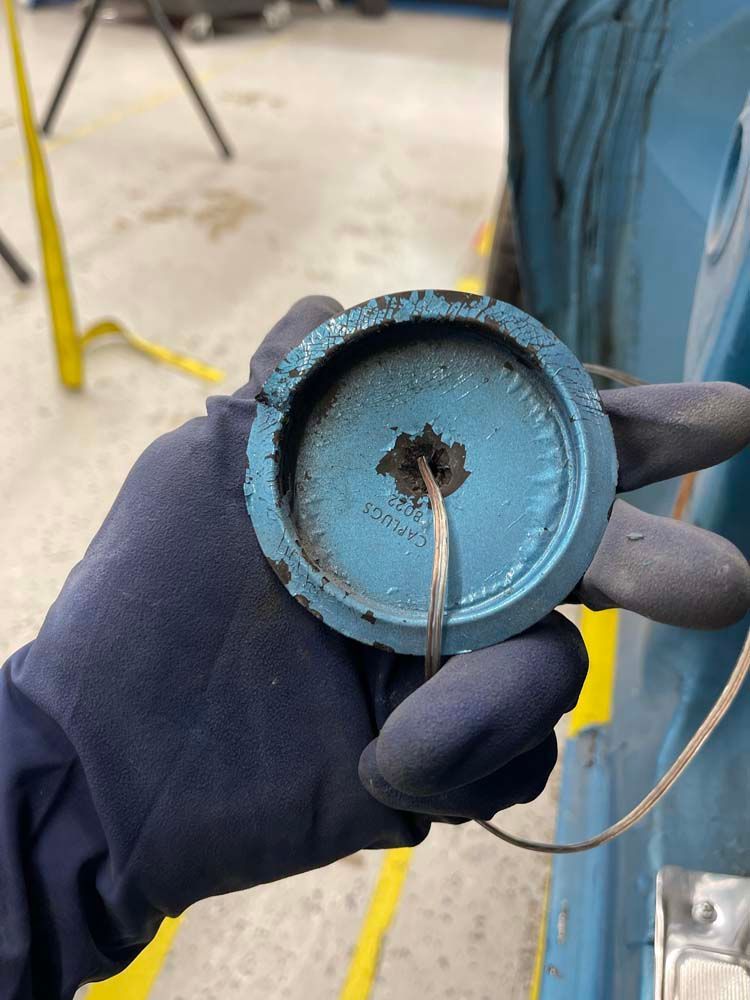 A person wearing gloves is holding a blue object in their hand