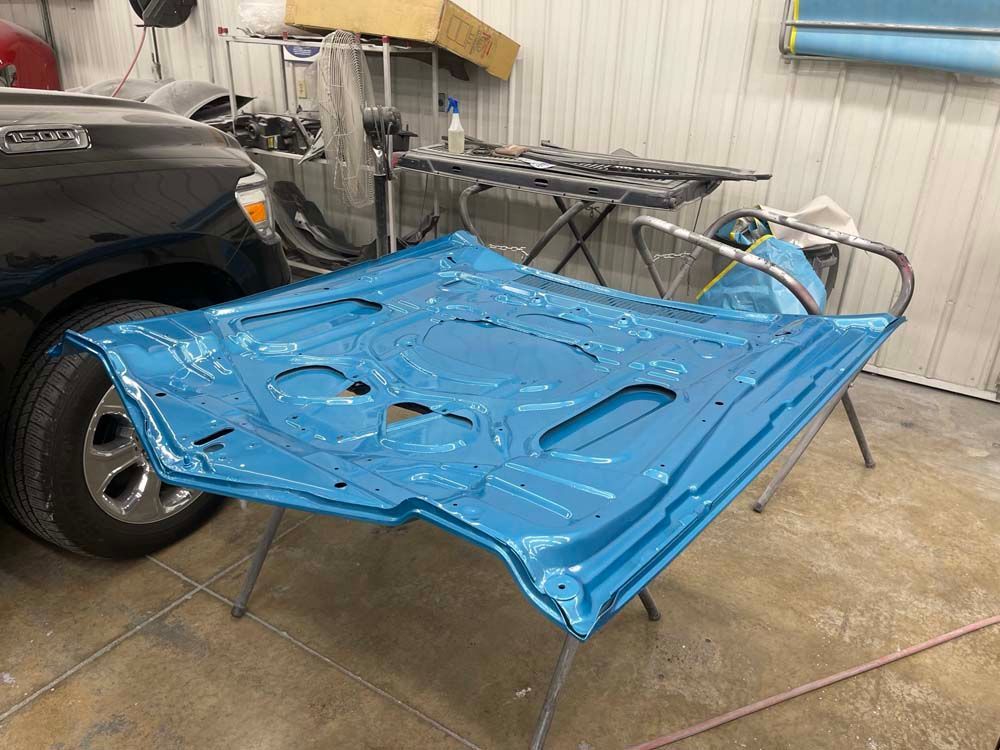 The hood of a car is sitting on a table in a garage.