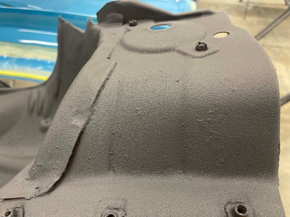 A close up of a piece of metal covered in black paint.