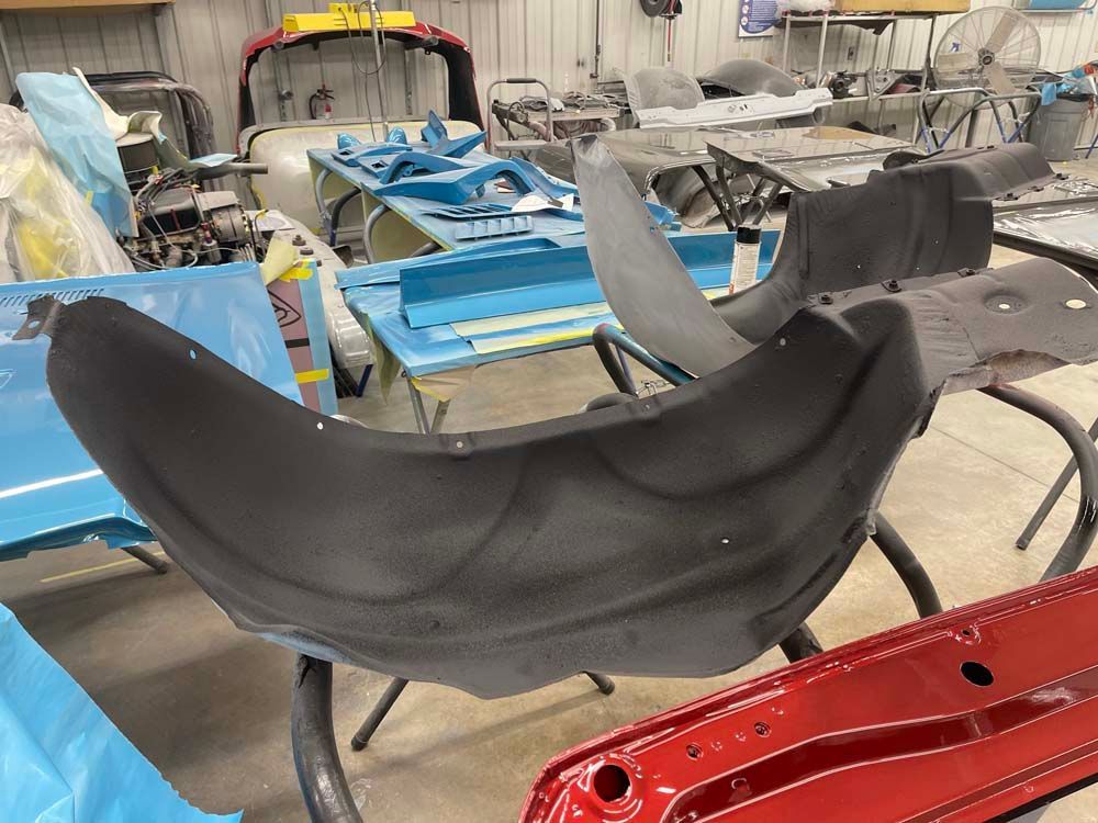 A bunch of car parts are sitting on tables in a garage.