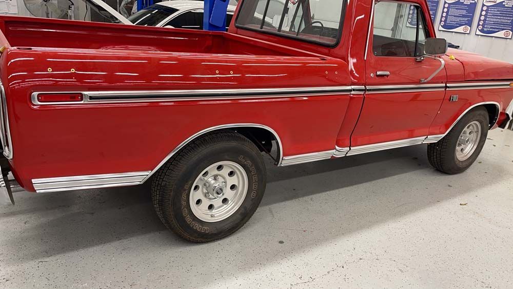 A red pickup truck is parked in a garage.