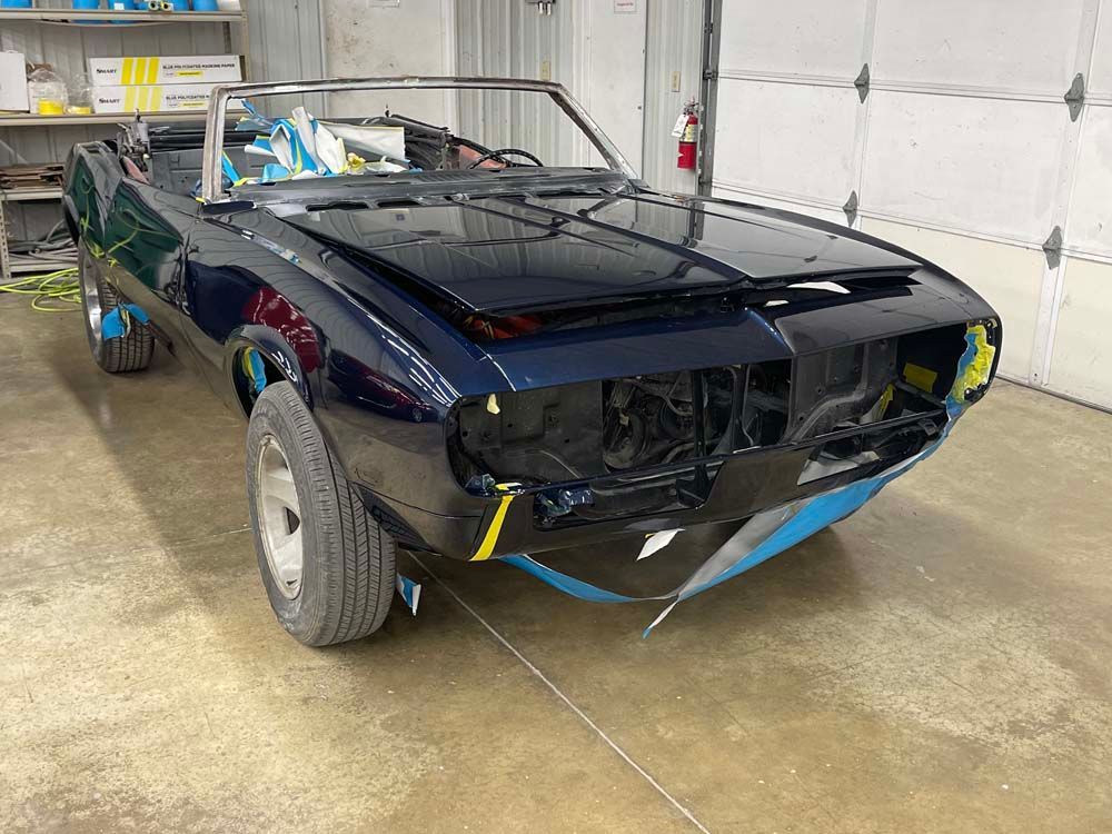 A black convertible car is being built in a garage.