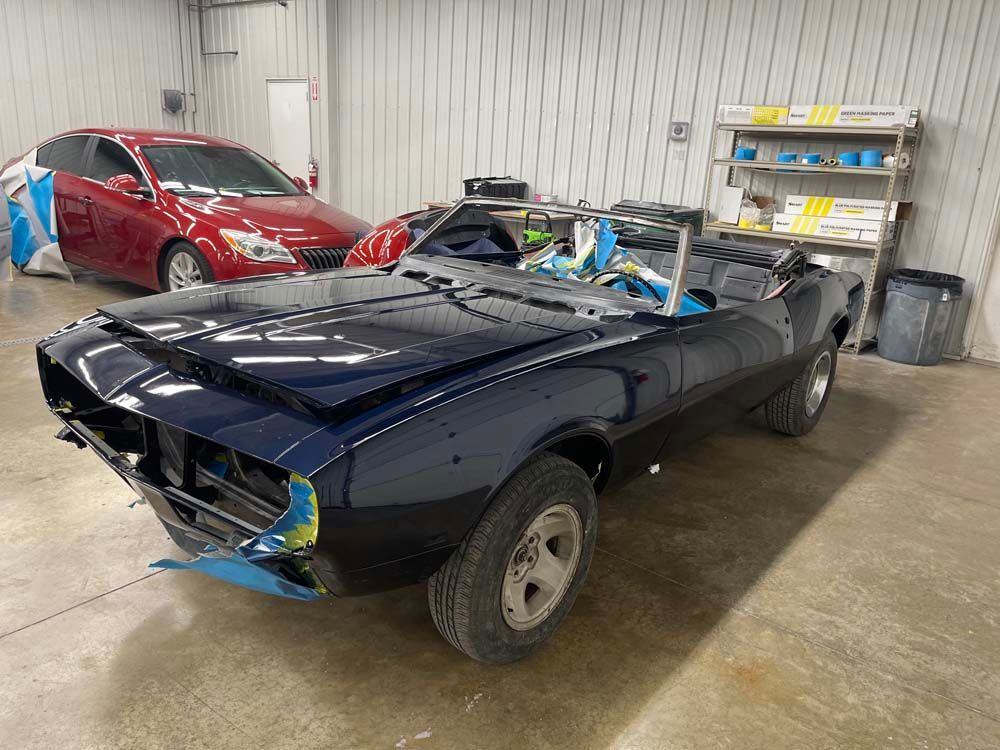 A black car is sitting in a garage next to a red car.