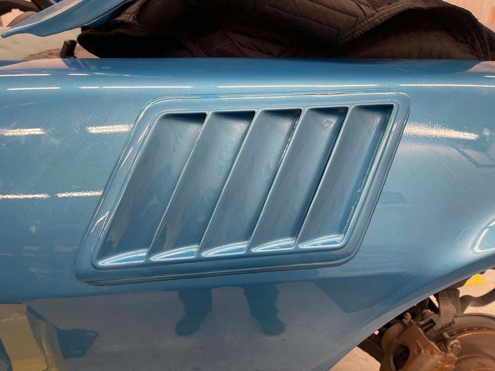 A close up of a blue car with a hood scoop