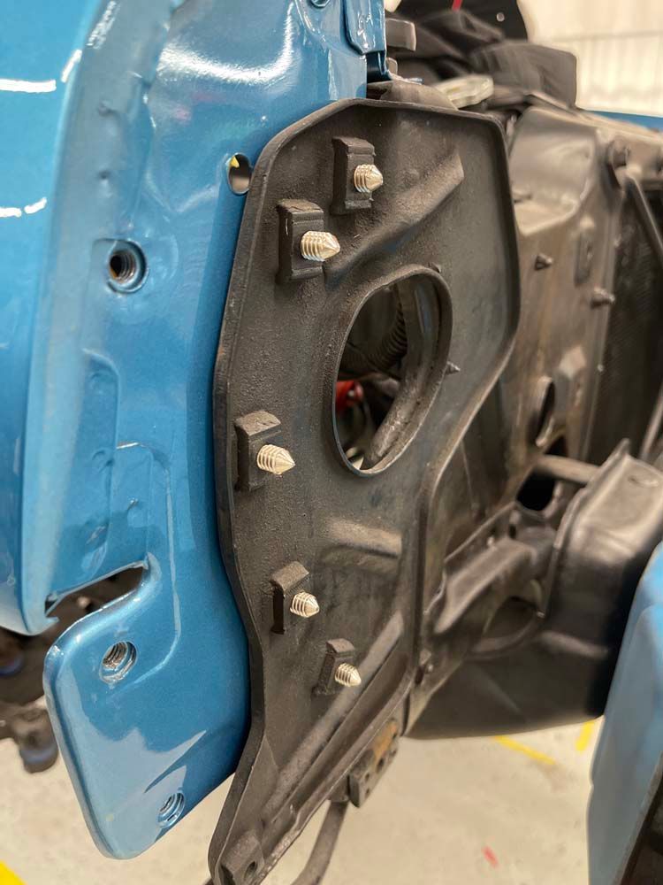 A blue car is being worked on in a garage.