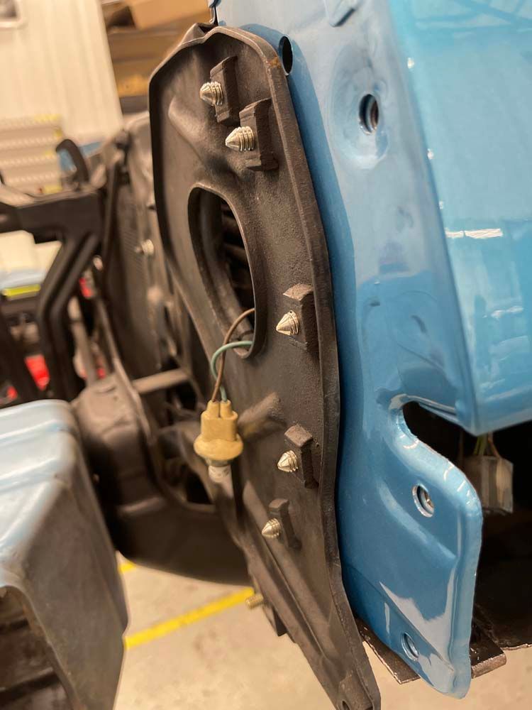 A close up of a blue car with the fender removed.