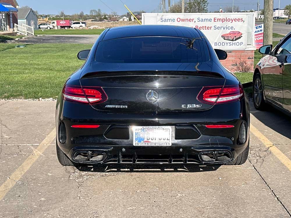A black mercedes benz c class is parked in a parking lot.