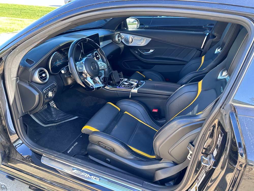 The interior of a black car with yellow seats and a steering wheel.