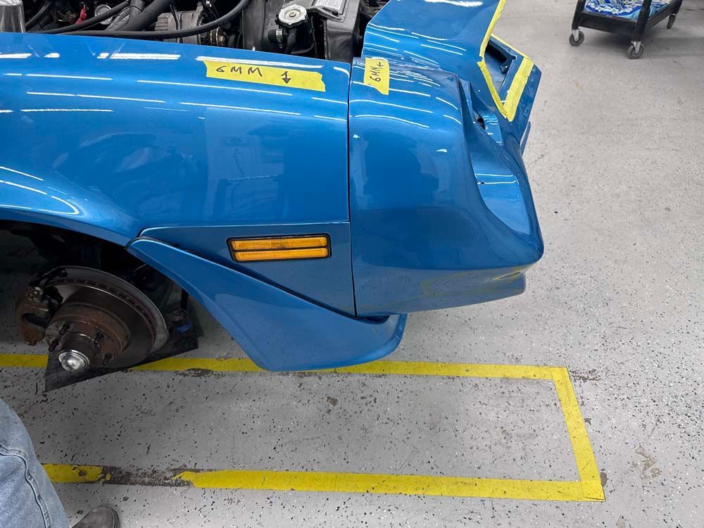 A blue car is sitting in a garage with a yellow stripe on the floor