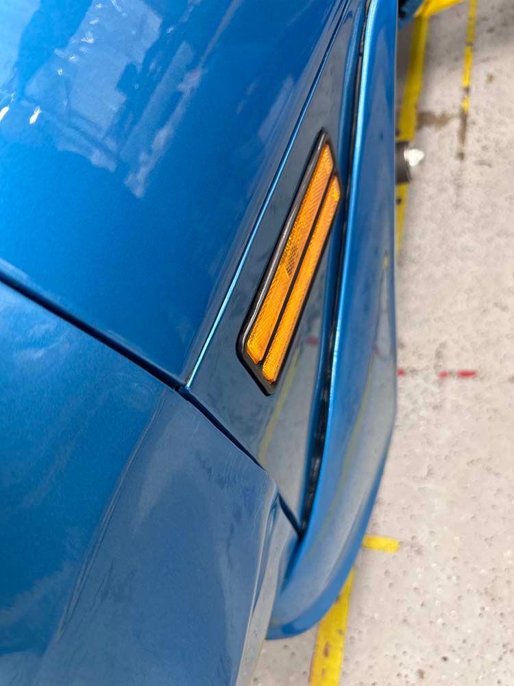 A close up of a blue car with yellow side lights