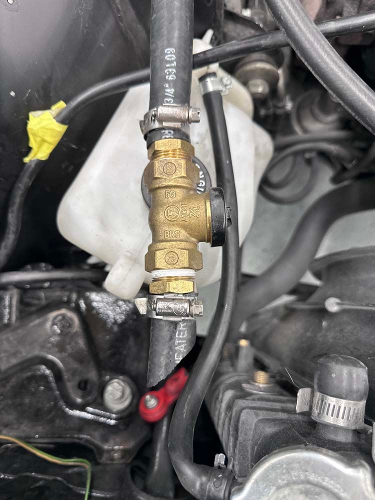 A close up of a car engine with a hose attached to it.