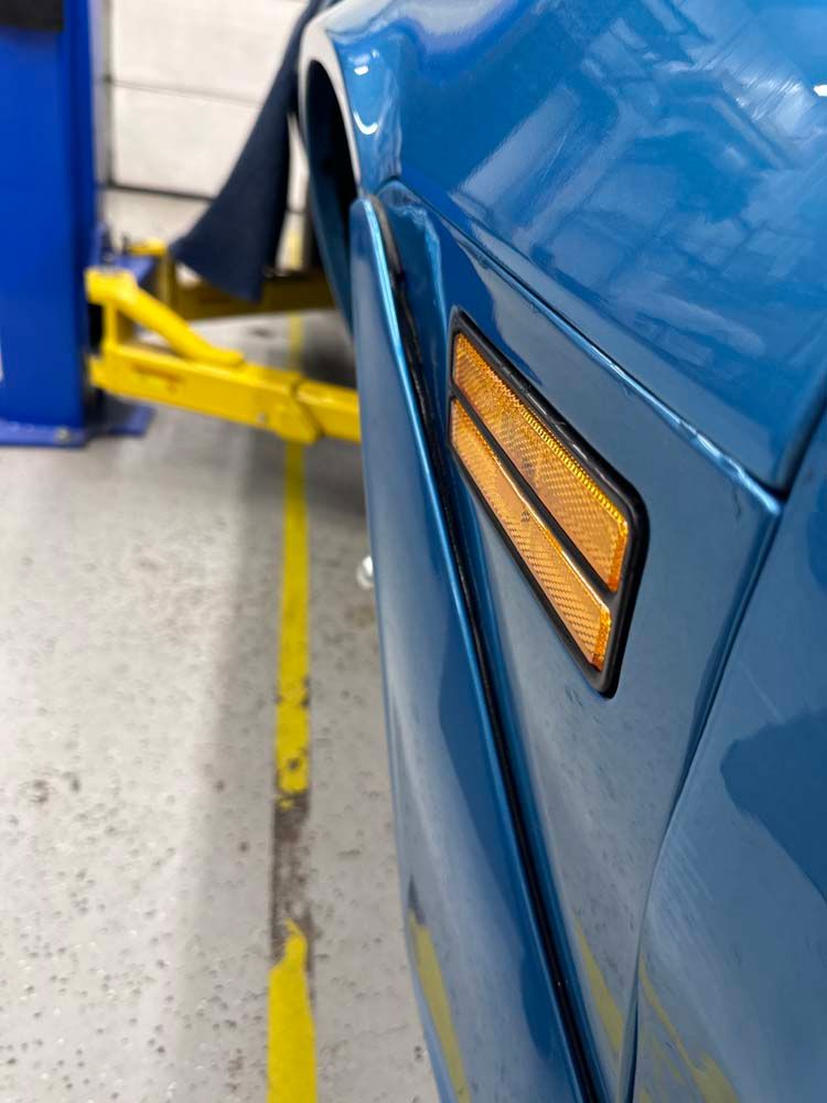 A blue car is sitting on a lift in a garage.