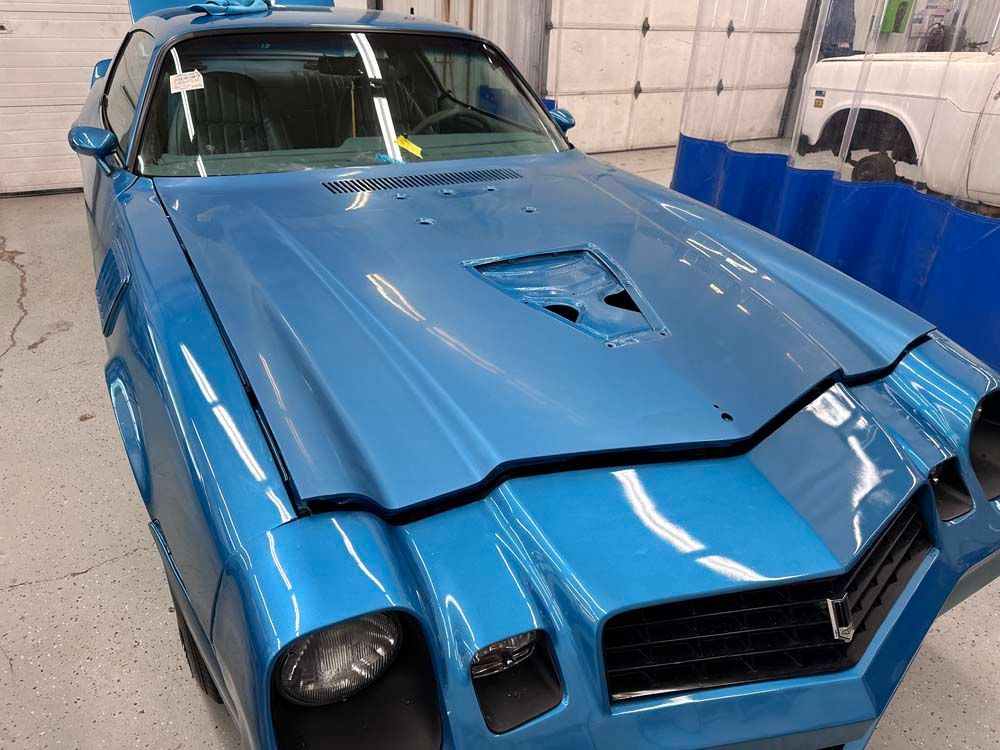 A blue car is parked in front of a garage door