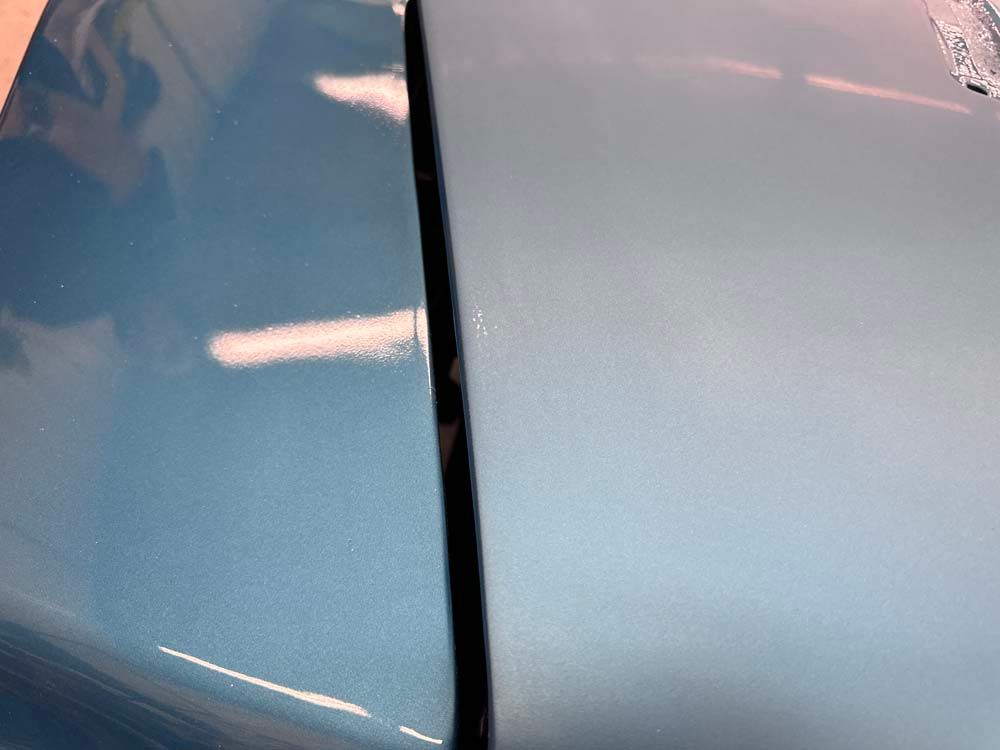 A close up of the hood of a blue car.