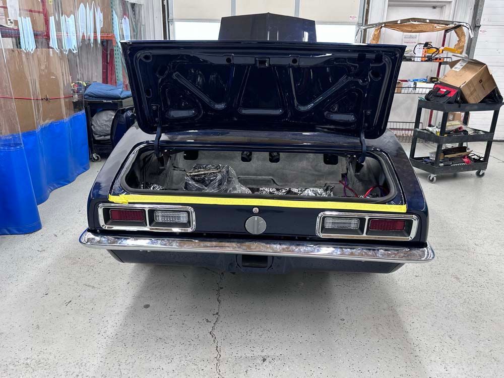 A black car with the trunk open is sitting in a garage.