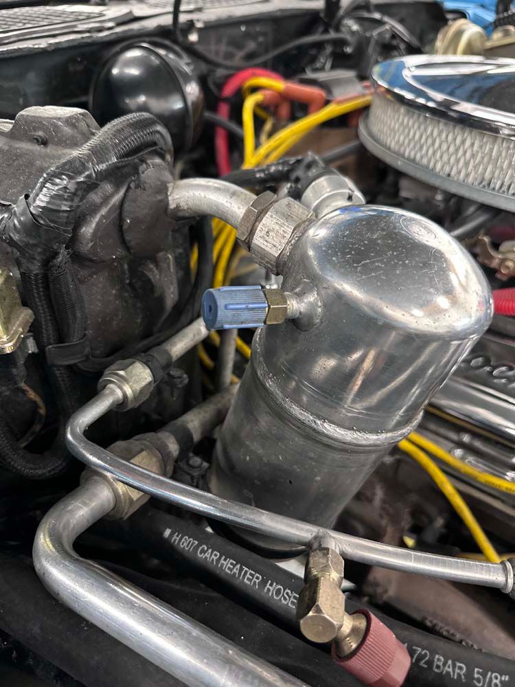 A close up of a car engine with a hose attached to it.