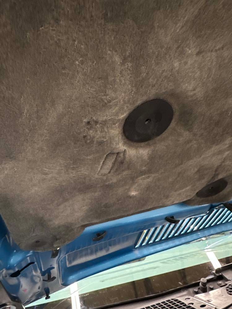 A close up of the underside of a car hood.